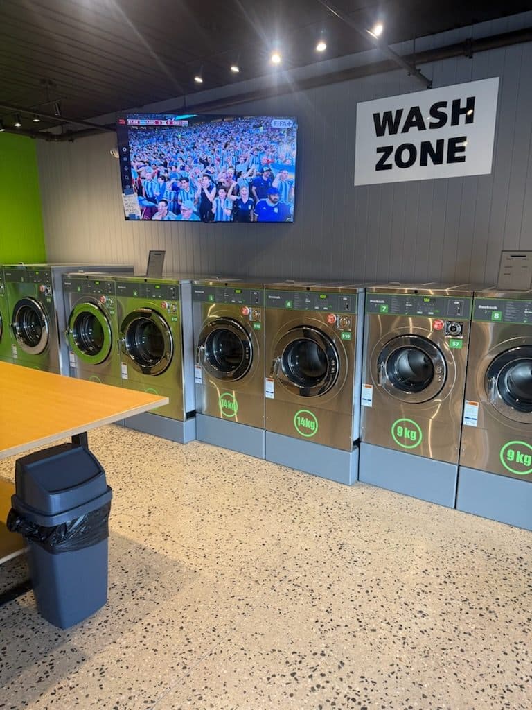 Row of front-load washing machines in the wash zone at Preston Laundry House